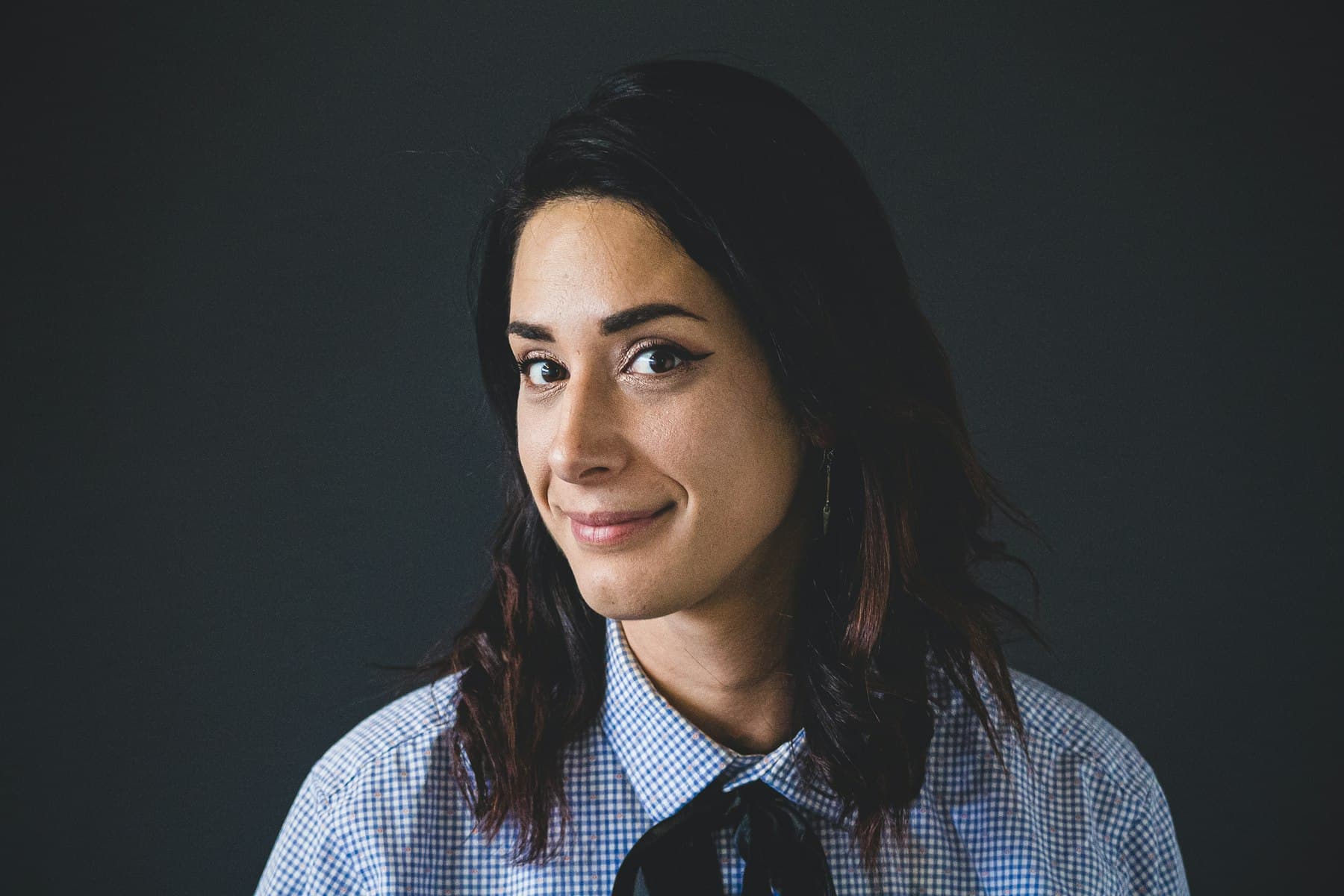 Woman in a checked shirt against a dark background